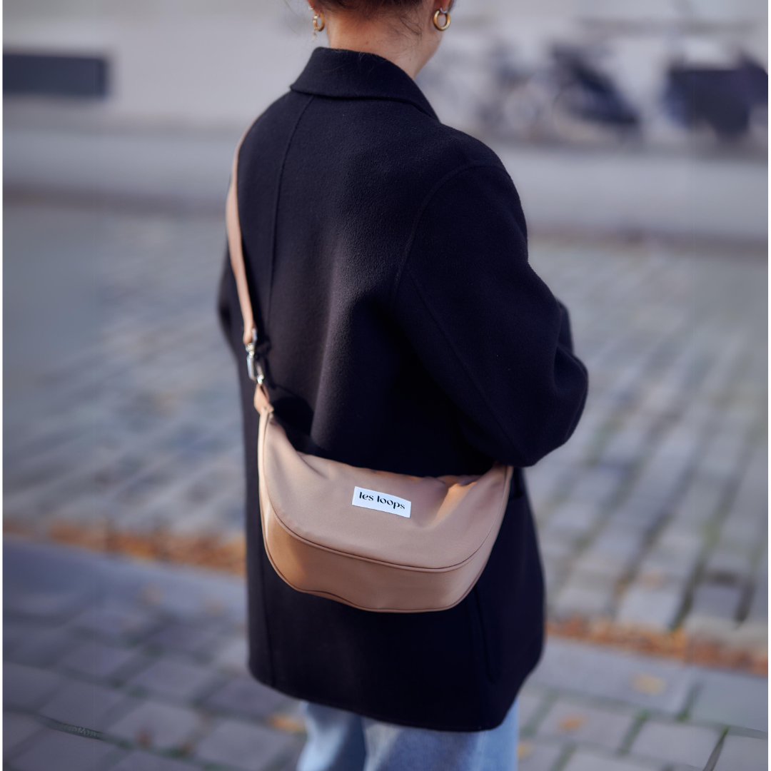 Die halbmondförmige Crossbody Bag in der Trendfarbe Salted Caramel kann über der Schulter getragen werden