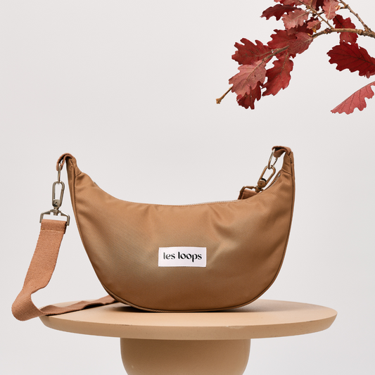 Die halbmondförmige Crossbody Bag Salted Caramel mit stabilem Boden kann aufrecht auf einem Tisch stehen